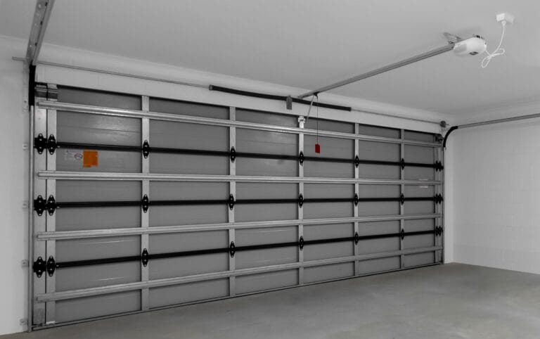 Internal view of a sectional garage door's hardware, including the track, rollers, and panel hinges. - Gliderol