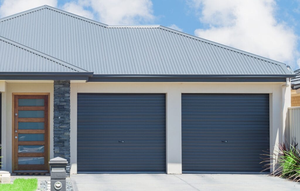 A modern home featuring two matching blue Gliderol roller garage doors side-by-side - Gliderol