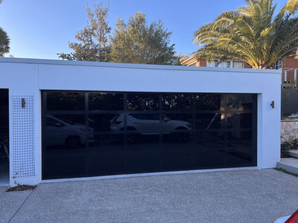 Danmar_Clearlight_Grey Glasslite_04_Aug2025 Gliderol Danmar Glasslite garage door featuring toughened glass panels and a black frame. - Gliderol